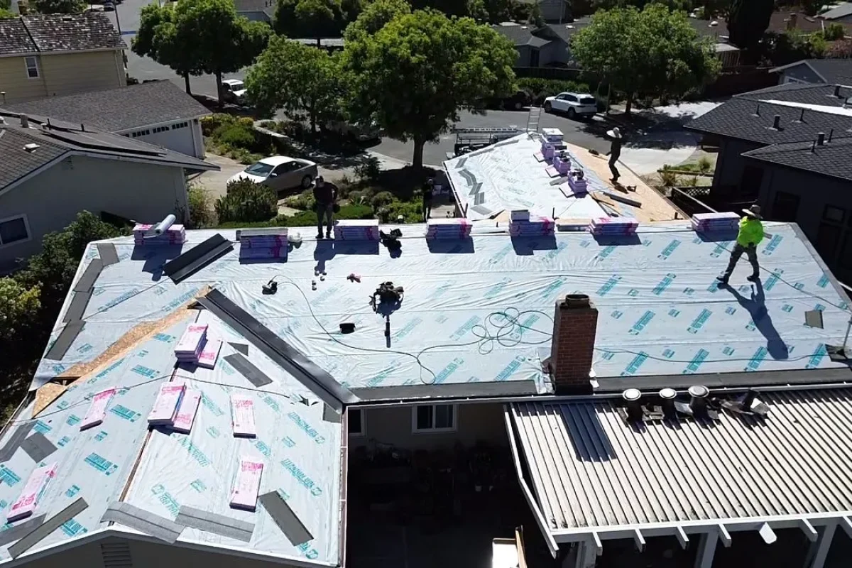 Aerial view of a roof replacement in progress with underlayment installed and shingle bundles staged on the roof